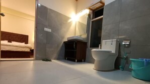 A modern bathroom with a toilet, a sink, and a shower area. - Gopa Residency Temisgam Village  (Leh)