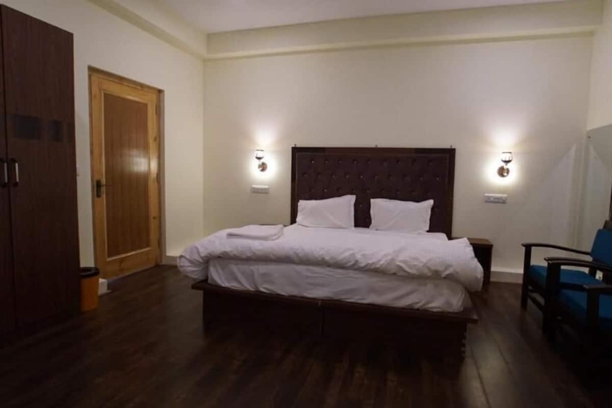 Quarto com uma cama grande, duas mesas de cabeceira, um guarda-roupa e uma cadeira.