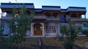 A multi-story building with a traditional architectural style, featuring balconies and large windows. - Gopa Residency Temisgam Village  (Leh)