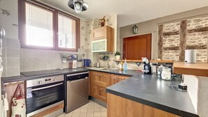 A modern kitchen with a dishwasher, oven, and a coffee maker on the counter. - Appartement Centre-ville Proche Paris et Versailles (Sèvres)