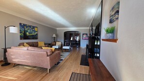 Una sala moderna con un sofá rosa, un cuadro en la pared y un área de comedor con sillas y una mesa.