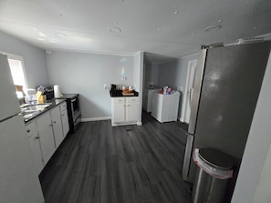 A compact kitchen with a refrigerator, microwave, sink, and a washing machine.