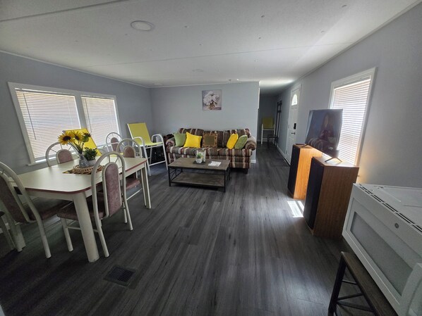 A living room with a dining table, chairs, a sofa, a coffee table, and a television.