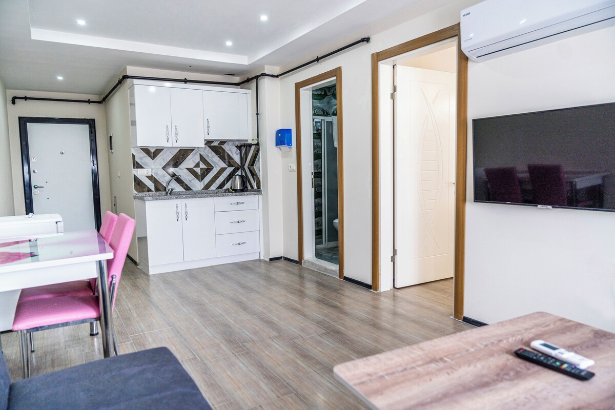 Et moderne køkken med hvide skabe, et mønstret backsplash og et spiseområde med pink farvede stole.