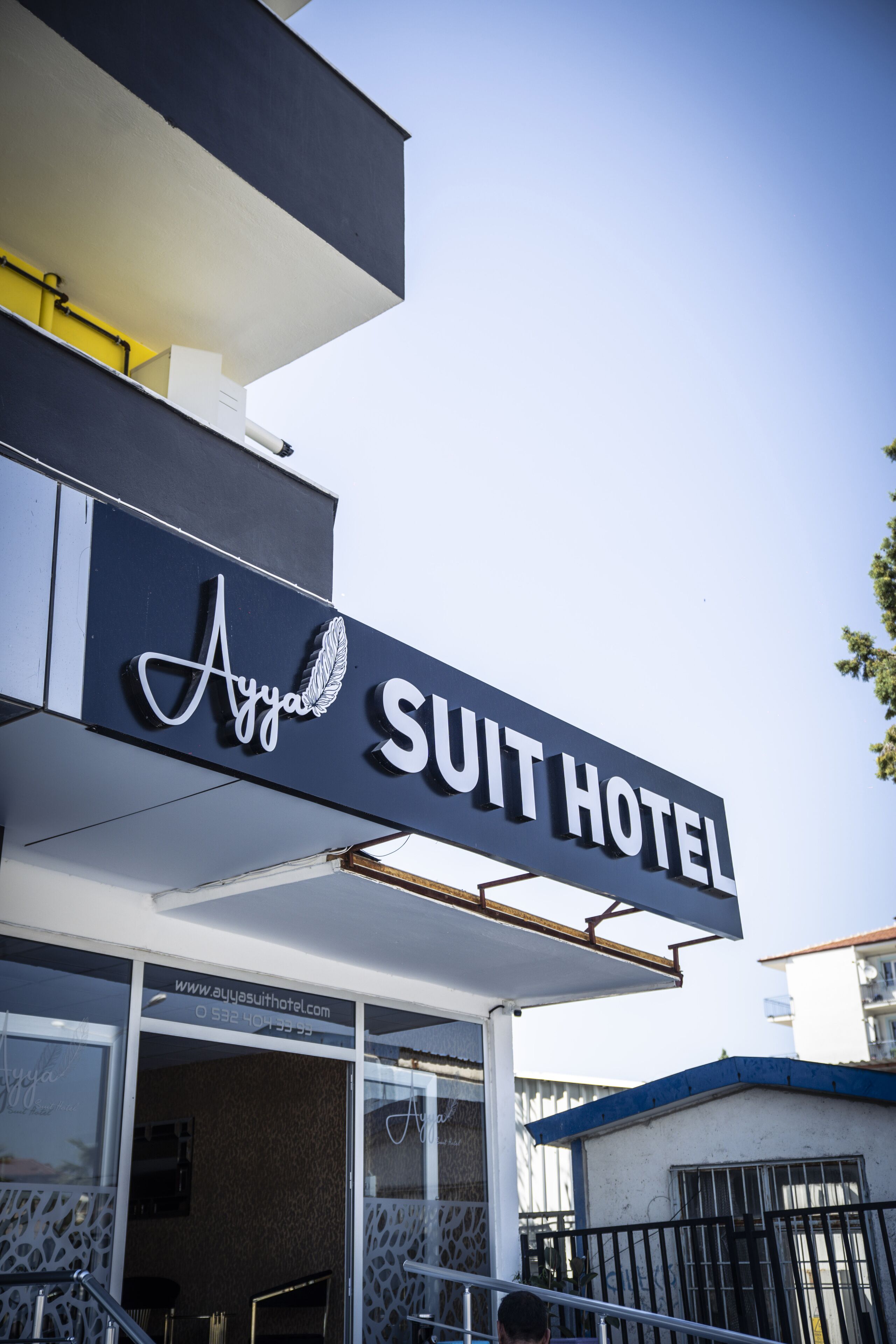 A hotel sign with the name "Ayya Suit Hotel" and a website URL.