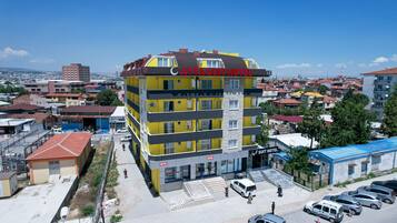 A multi-story hotel with a yellow facade and a red roof, featuring a prominent sign for the "CAYYA SUIT HOTEL".
