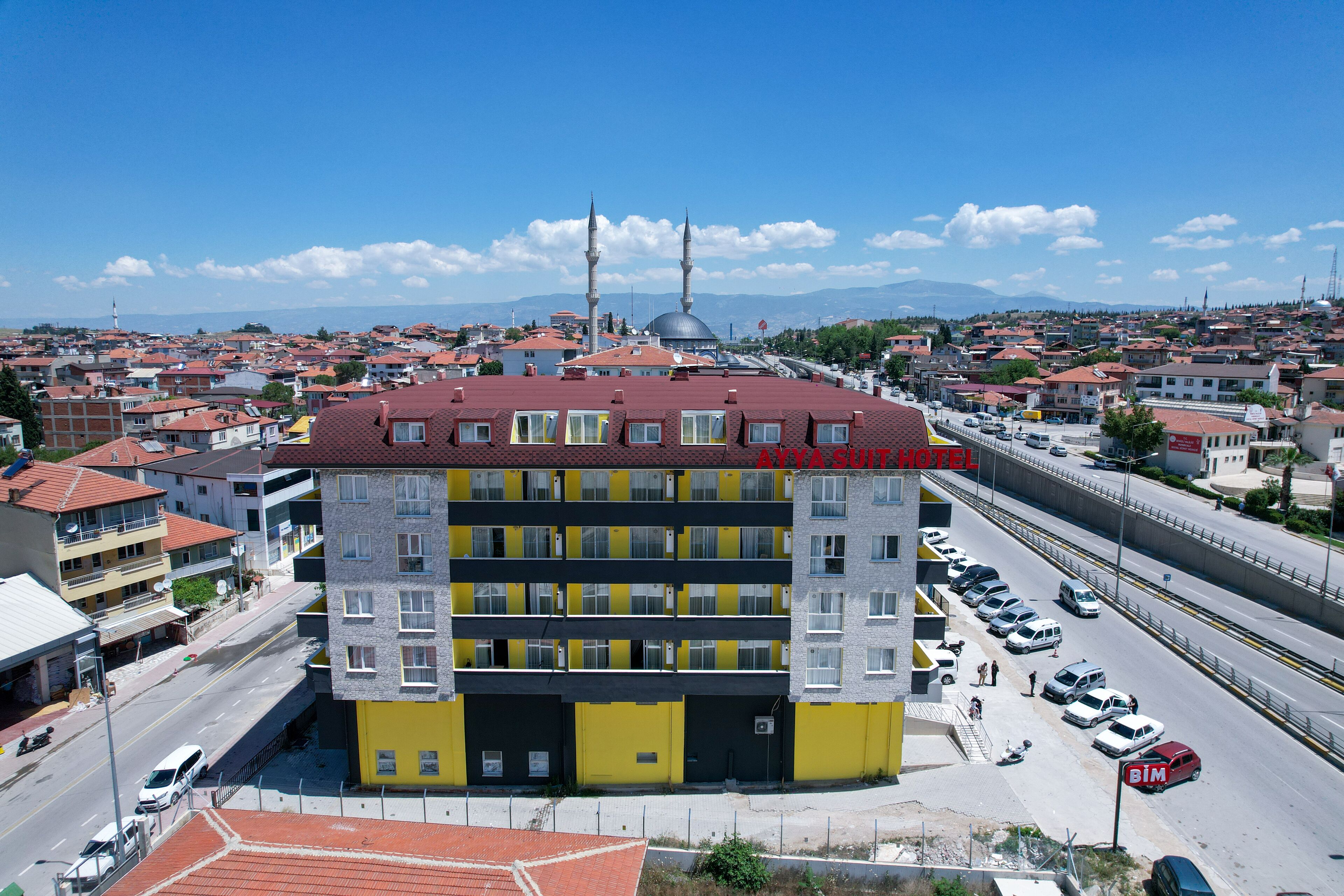 Un hotel de varios pisos con una fachada amarilla destacada, techo rojo y dos minaretes al fondo.