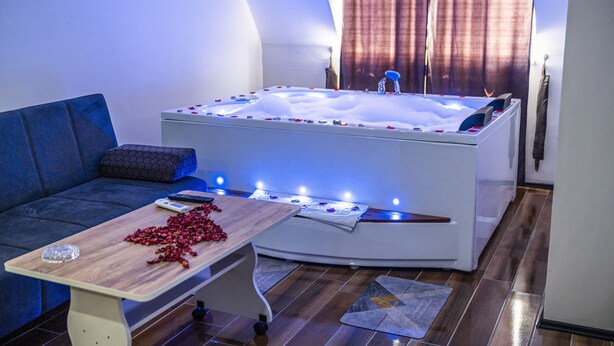 Un baño moderno con una bañera independiente, una mesa de madera con pétalos de rosa y un sofá azul.