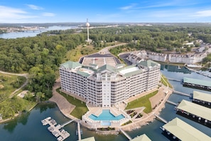 Stunning hotel with a central courtyard and pool, overlooking a marina and lush surroundings.