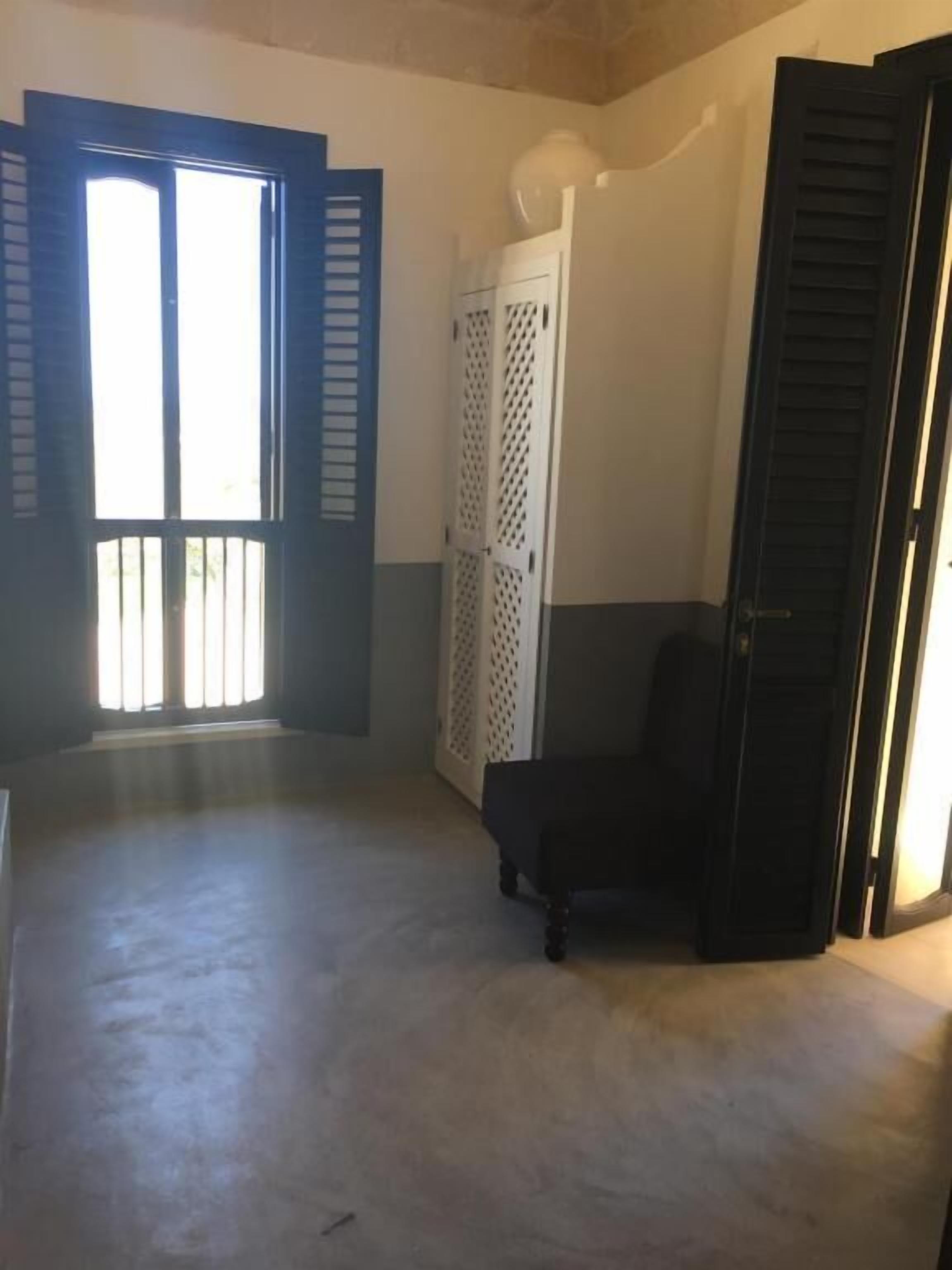 A room with a large window, a closed door, and a chair.