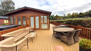 A wooden deck with wicker furniture, a barbecue area, and a view of a forested landscape.