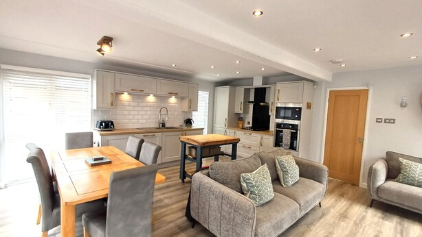 A modern apartment with a dining area, sofa, and kitchen.