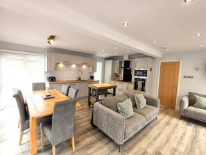 A modern apartment with a dining area, sofa, and kitchen.