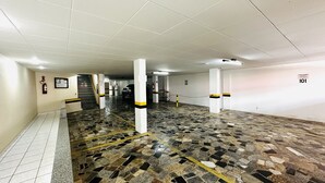 A parking garage with white tiled walls, numbered parking spaces, and a tiled floor with yellow lines.