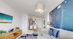En moderne stue med sofa, spiseområde, køkken og et stort verdenskort.