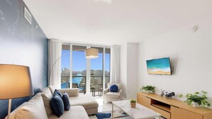 A modern living room with a sofa, coffee table, and TV. - Pool + Infinity View w/ Balcony + Gym (Hallandale Beach)