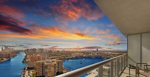 A balcony with a view of a cityscape, a river, and a marina with boats.