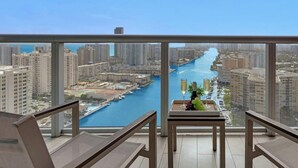 A balcony with a view of a river and cityscape, a table with a bottle and grapes, and two chairs. - Upper studio  w/Balcony + Pool + Gym- Near Beach (Hallandale Beach)