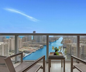A balcony with a view of a river, high-rise buildings, and a clear sky.