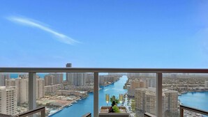 Een balkon met uitzicht over de stad en een rivier, een tafel met een fles en glazen, en twee stoelen.