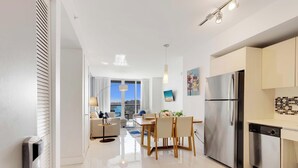 Een moderne keuken met een roestvrijstalen koelkast, een eethoek met een tafel en stoelen, en een uitzicht op de stad door grote ramen.