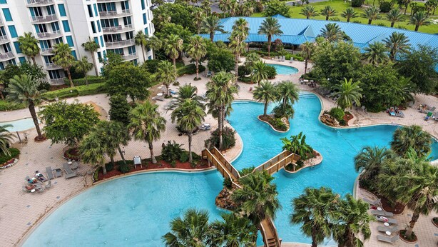 A resort with multiple swimming pools surrounded by palm trees and lounge areas.