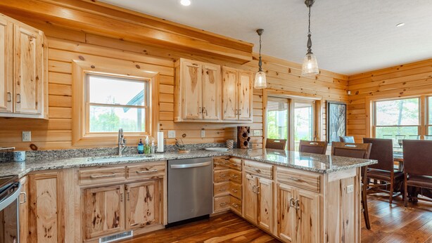 A spacious kitchen with wooden cabinets, granite countertops, and a central island. - Dog Friendly Mountain Lodge w/ Hot Tub (McHenry)