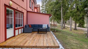 A red building with a wooden deck, a sofa, and a table.