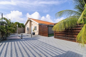 A building with a tiled roof, a paved walkway, and a palm tree.