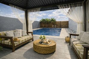 A poolside area with two sofas, a round wicker table, and a small pool. - Grill, Chill & Gazebo Thrill – Solito’s Best 3-BDR Stay Yet (Oranjestad)