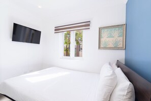 A bedroom with a bed, a TV mounted on the wall, a window with blinds, and a framed picture on the wall. - 3-BR Private Pool Paradise - BBQ Grill - Gazebo (Oranjestad)