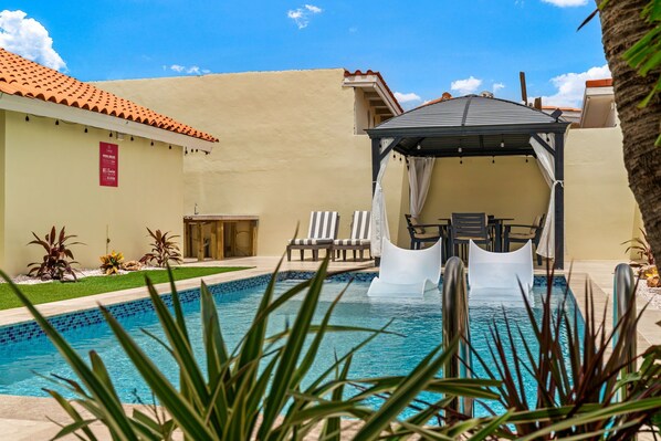 Ein Schwimmbecken mit Gazebo, Liegestühlen und einer Poolanlage.