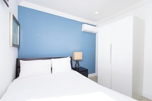 Ein Hotelzimmer mit einem Bett, einem Nachttisch, einer Lampe, einer Klimaanlage und einem Kleiderschrank.