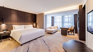 Una habitación de hotel moderna con una cama grande, un sofá, un escritorio y una televisión.