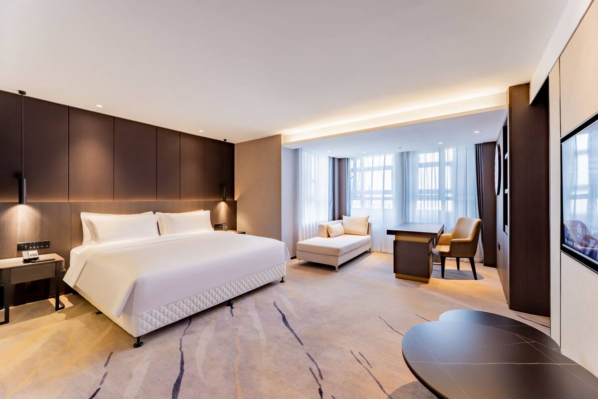 Una habitación de hotel moderna con una cama grande, un sofá, un escritorio y una televisión.
