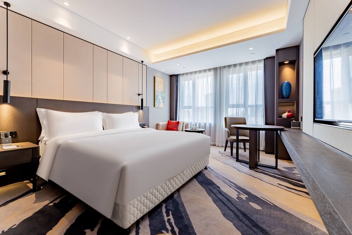 Una habitación de hotel moderna con una cama grande, un escritorio y una zona de estar.