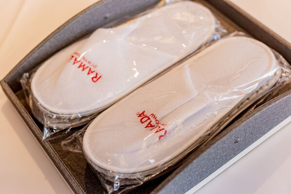 A tray with two white slippers wrapped in plastic, labeled with "RADA". - Ramada by Wyndham Bayannur (Bayan Nur)