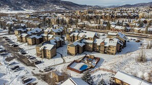 Un quartier résidentiel comprenant plusieurs immeubles à deux étages, un parking et une piscine.