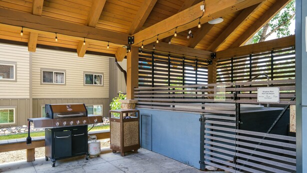 An outdoor barbecue area with a grill, a gas tank, and a hot tub sign.
