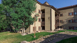 A multi-story building with a balcony, a stone pathway, and a well-maintained lawn.