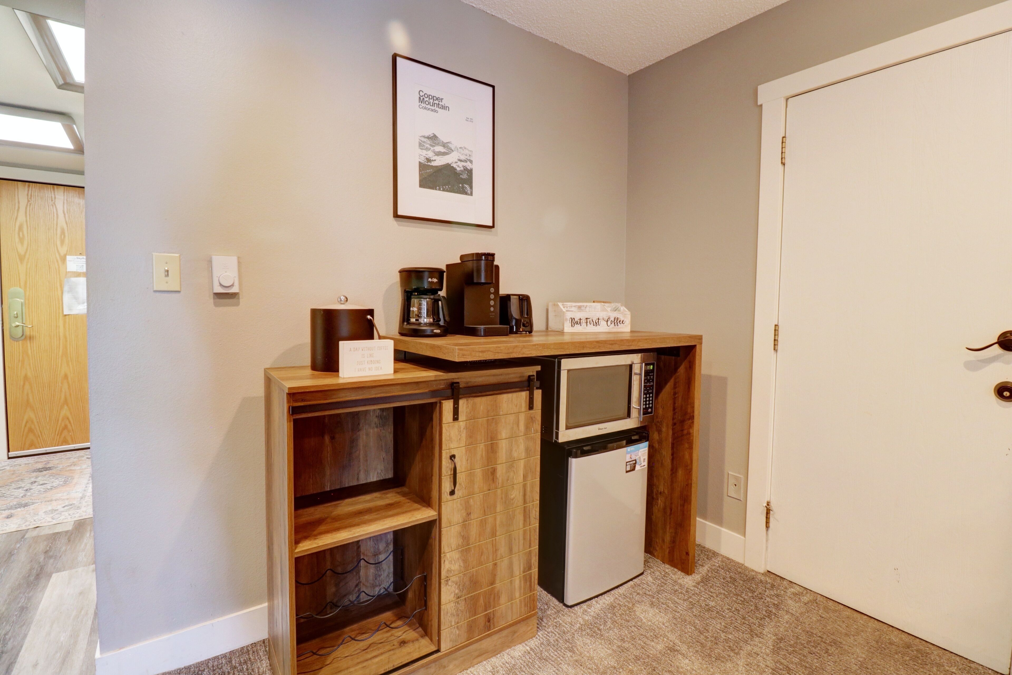 A compact kitchenette with a microwave, coffee maker, and a small refrigerator.