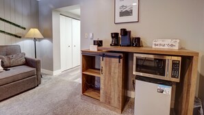 A compact living space with a kitchenette, including a microwave, coffee maker, and a small refrigerator. A sofa and a lamp are also visible. - Cm321h Copper Mtn Inn Hotel Room by RedAwning (Copper Mountain)