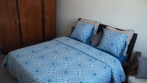 Un dormitorio con una cama, un armario de madera y una silla.