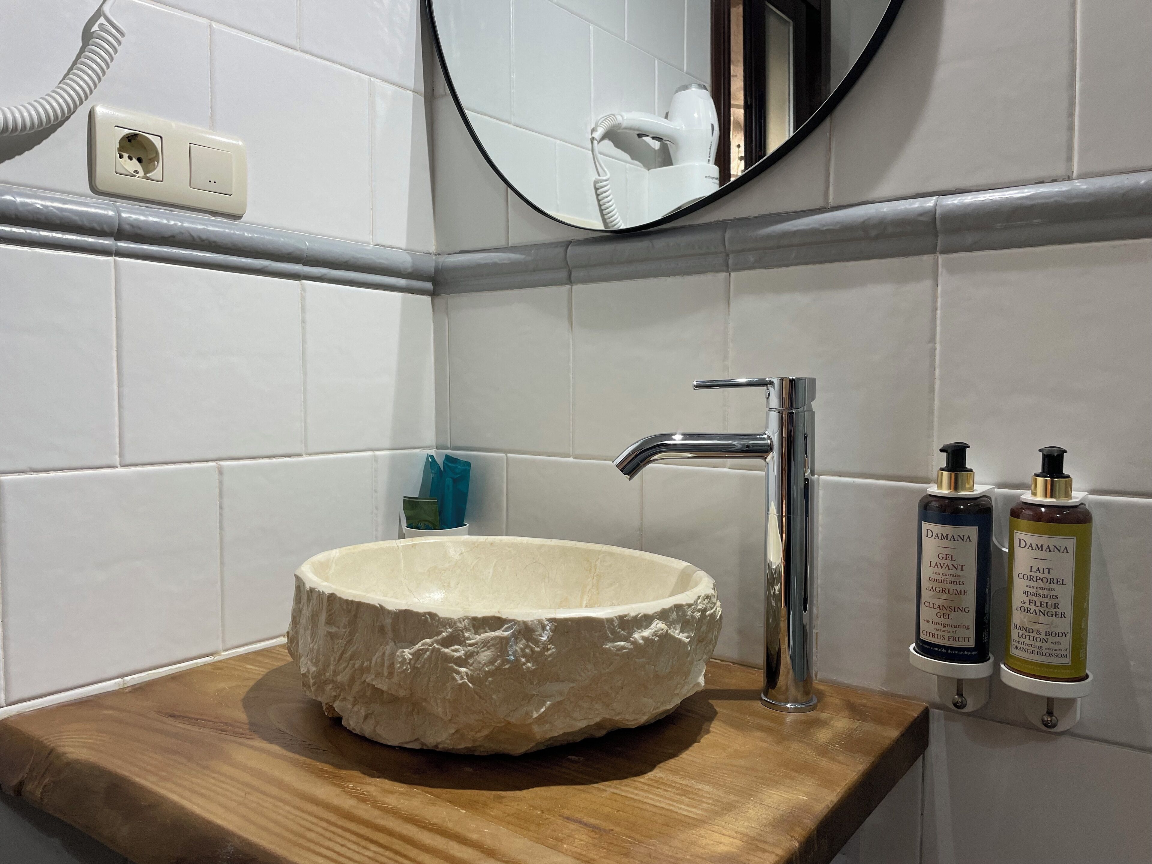 Ein Badezimmer mit einem Steinsink, einem modernen Wasserhahn und zwei Handlotionflaschen.