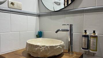 Ein Badezimmer mit einem Steinsink, einem modernen Wasserhahn und zwei Handlotionflaschen.