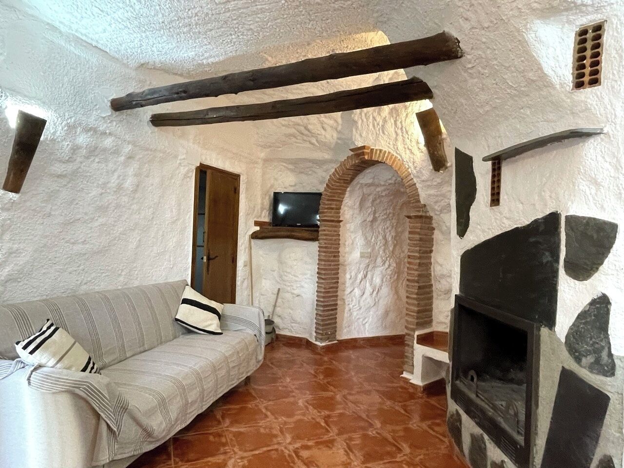 Una habitación acogedora y rústica con chimenea de piedra, un banco de madera y un sofá.