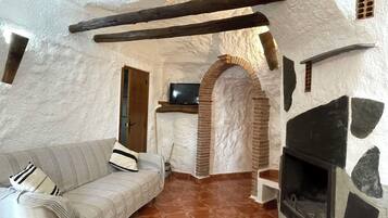 Una habitación acogedora y rústica con chimenea de piedra, un banco de madera y un sofá.
