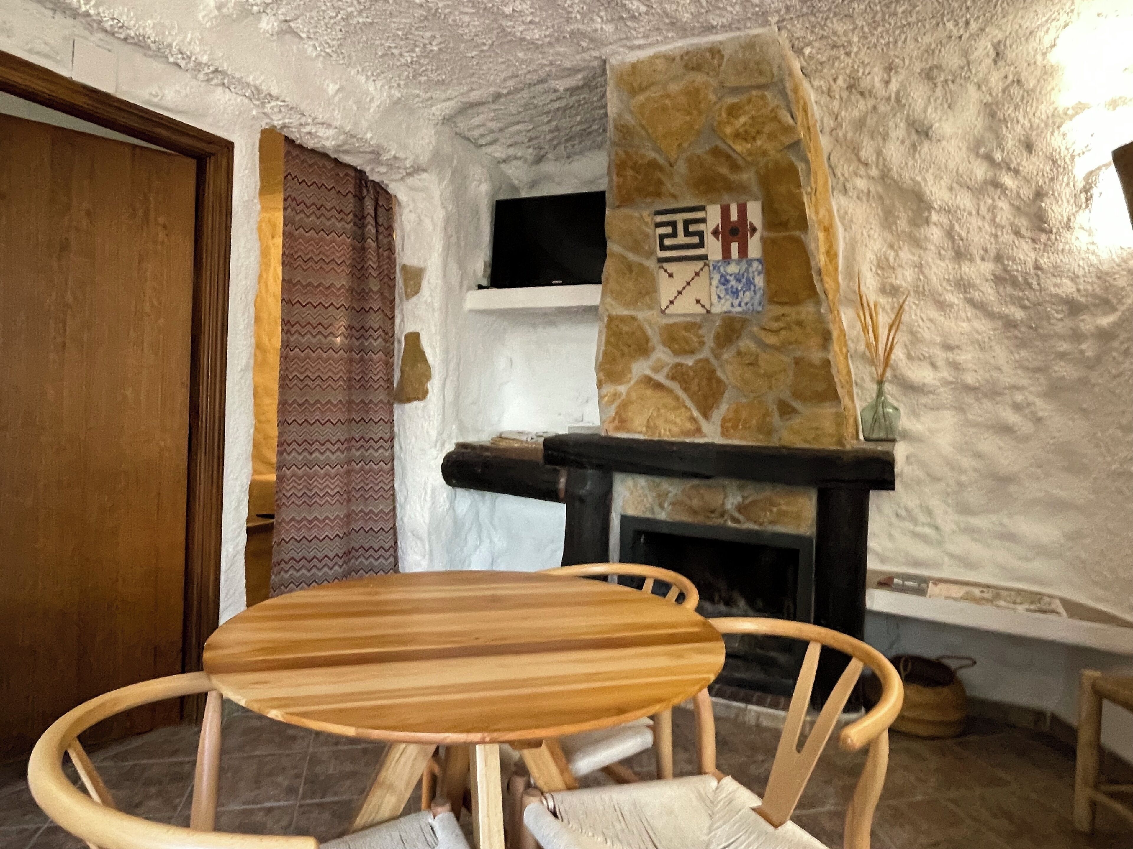 Une pièce avec une cheminée en pierre, une table en bois et une chaise.