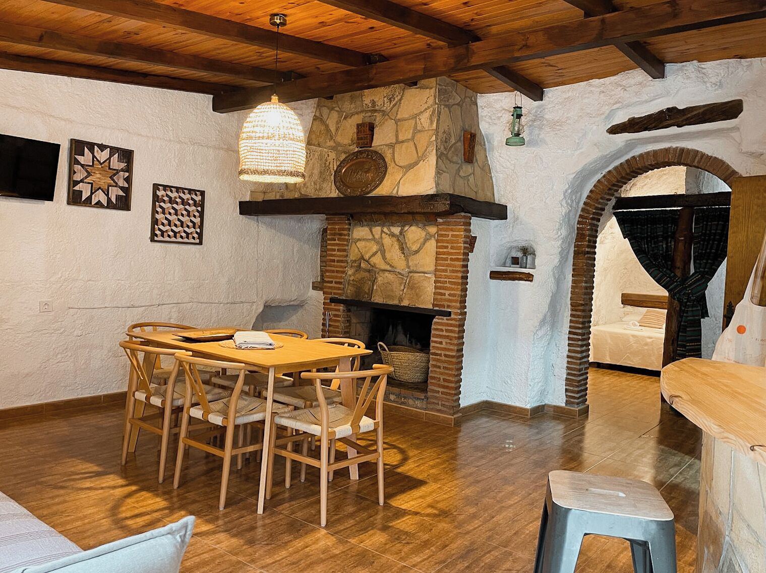 A rustic interior with a stone fireplace, wooden dining table, and chairs.
