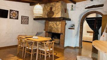 A rustic interior with a stone fireplace, wooden dining table, and chairs.